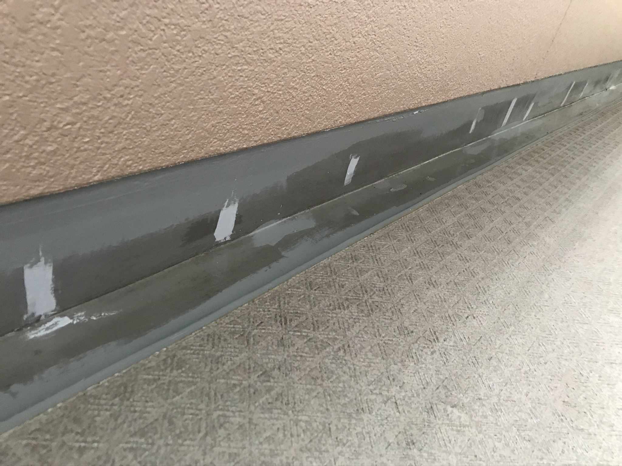 さいたま市北区マンション共用部廊下巾木＆排水溝の端に防水トップ用プライマー塗布